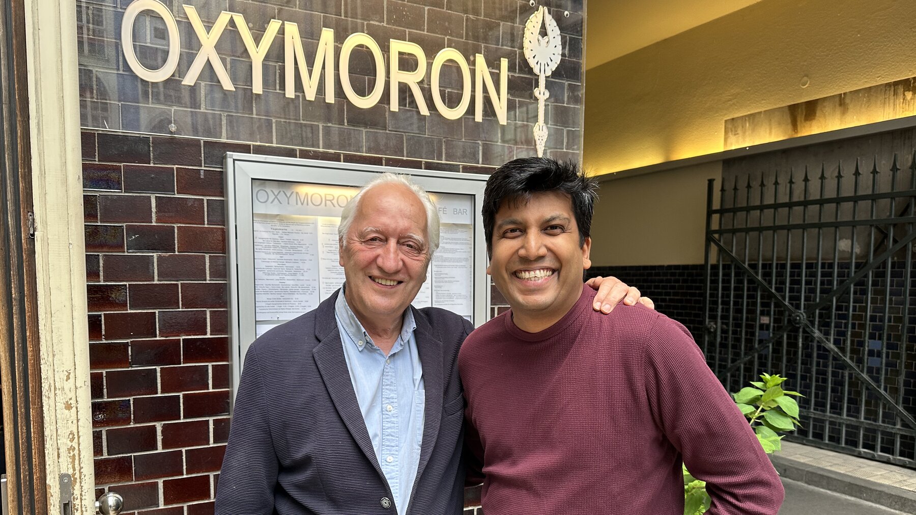 Charles Landry and Anupam Yog beneath the OXYMORON sign — Festival Co-Chairs of The Art of Citymaking