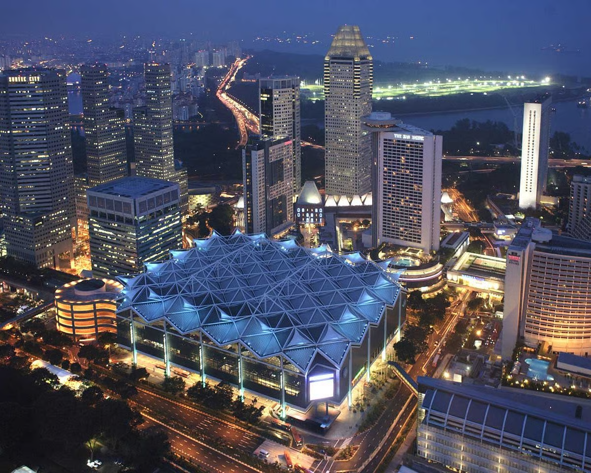 Aerial view of Singapore's Marina Centre at golden hour — Suntec City towers and the Fountain of Wealth in the foreground, with Marina Bay Sands and the Singapore Flyer beyond